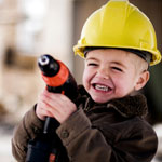 young boy wearing yellow hard hat and holding a toy drill